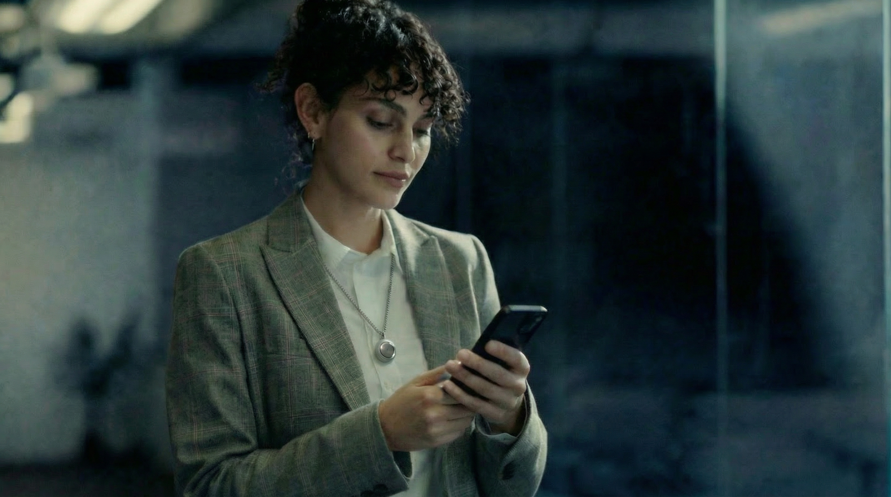 Woman wearing Omi AI pendant while using smartphone — real-world usage